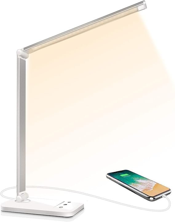 Une lampe de bureau LED moderne, blanche et articulée, avec une lumière chaude et un port USB pour charger un smartphone.