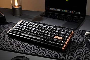 Clavier mécanique compact posé sur un bureau devant un pc portable.