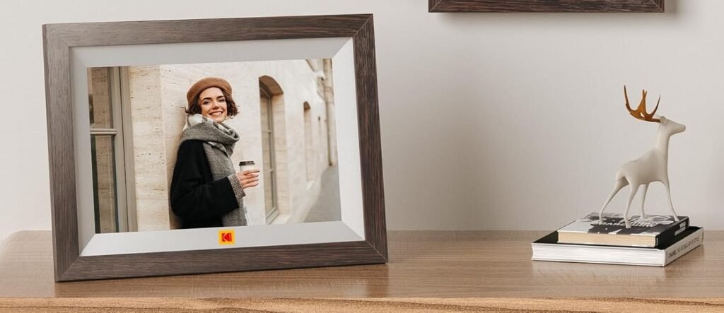 Cadre photo numérique Kodak : cadeau tech pour couple, affichant une femme souriante en béret avec café, sur table en bois avec statue cerf et livres, décor minimaliste.