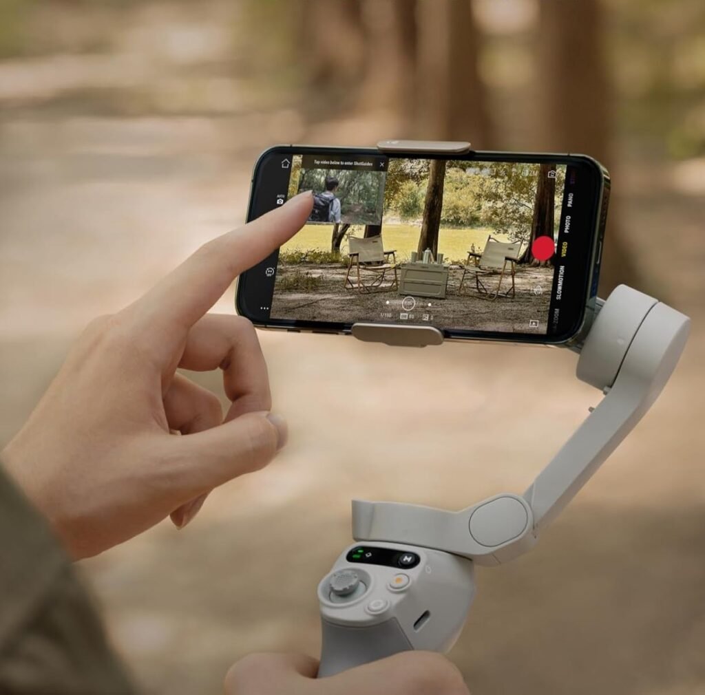 Stabilisateur gimbal DJI Osmo pour smartphone : cadeaux tech couple, main tenant iPhone en mode enregistrement vidéo outdoor, fond forestier flou.